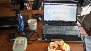 a laptop, a cup and orange peels on a table