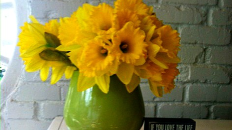 A green vase with yellow flowers