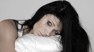 a melancholic face of a woman resting on a pillow