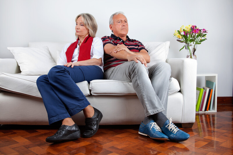 baby boomer couple sitting on couch arguing