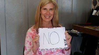A woman holding a placard inscribed with word 'no'