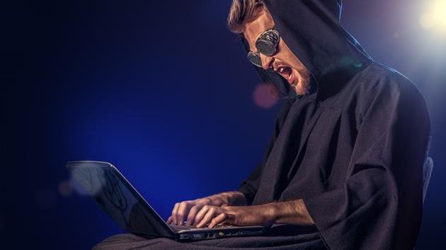 a man with a hood working on a laptop