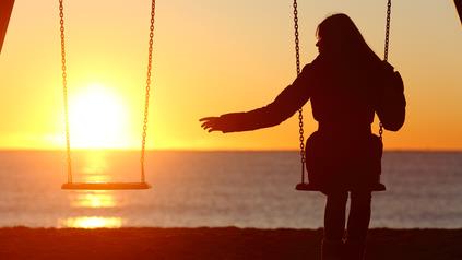 a woman on a swing during sunset at a beach