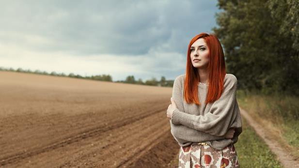 a redhead standing by a field