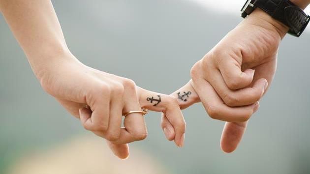 A couple holding fingers having tattoos