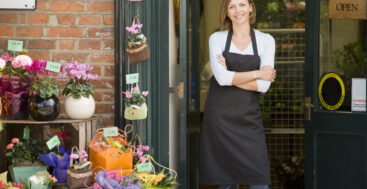 woman in work apron standing in front of a florist