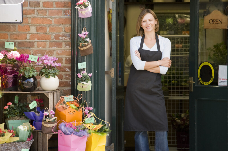 woman in work apron standing in front of a florist