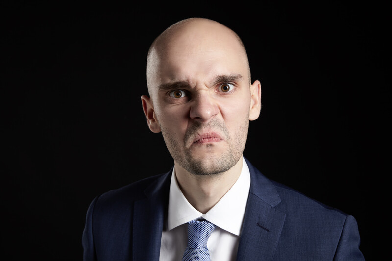 bald man in a suit with ugly grimace on his face