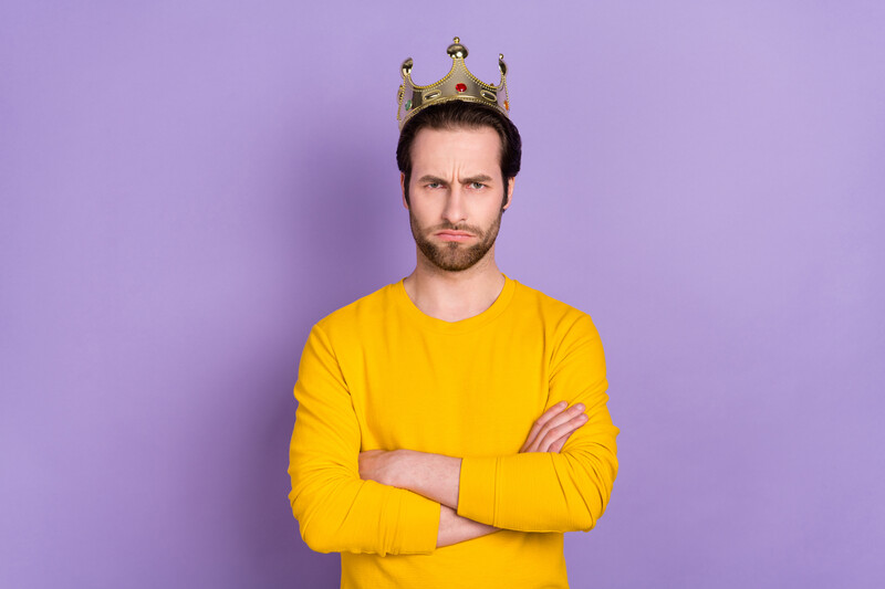 angry man wearing a crown in front of purple background