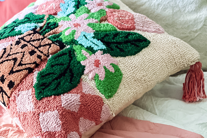 pink embroidered pillow on bed