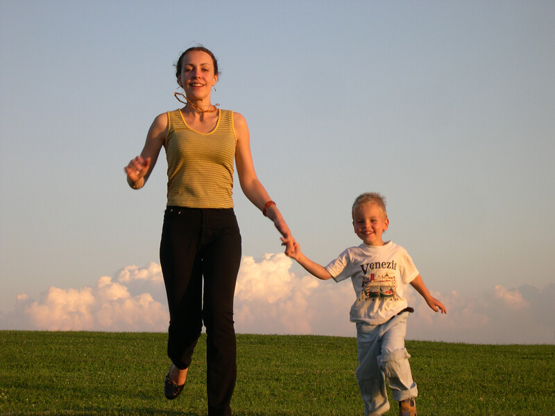 happy mother and son running, hand in hand, down a hill