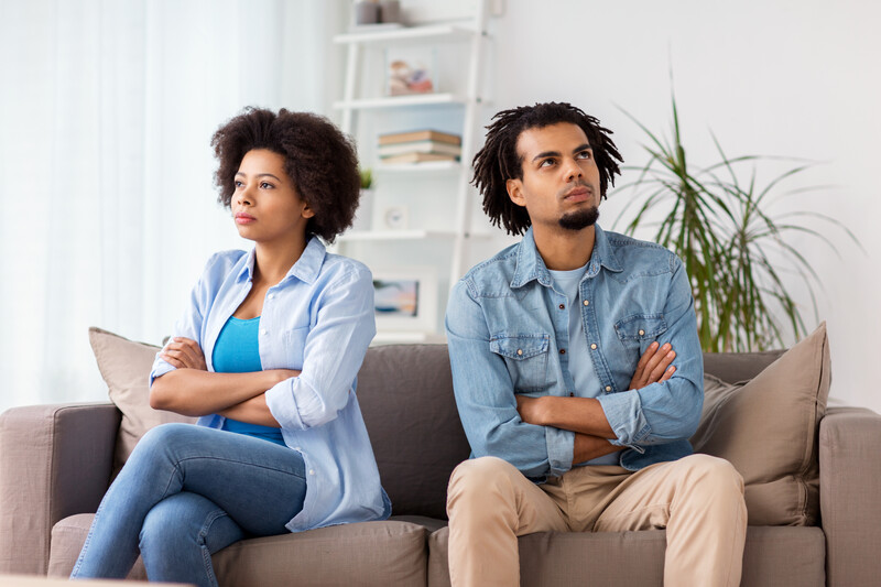 angry black couple sitting back to back on a sofa