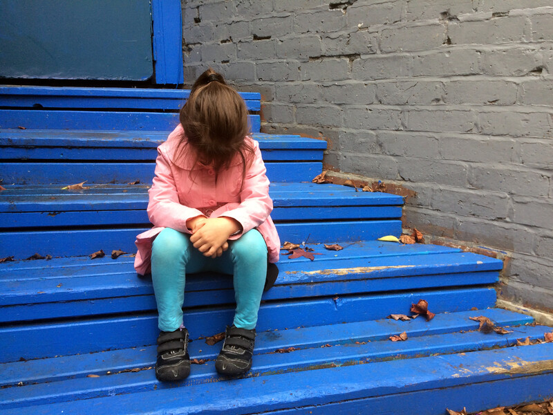 Little girl in pink sweater sitting with her head down